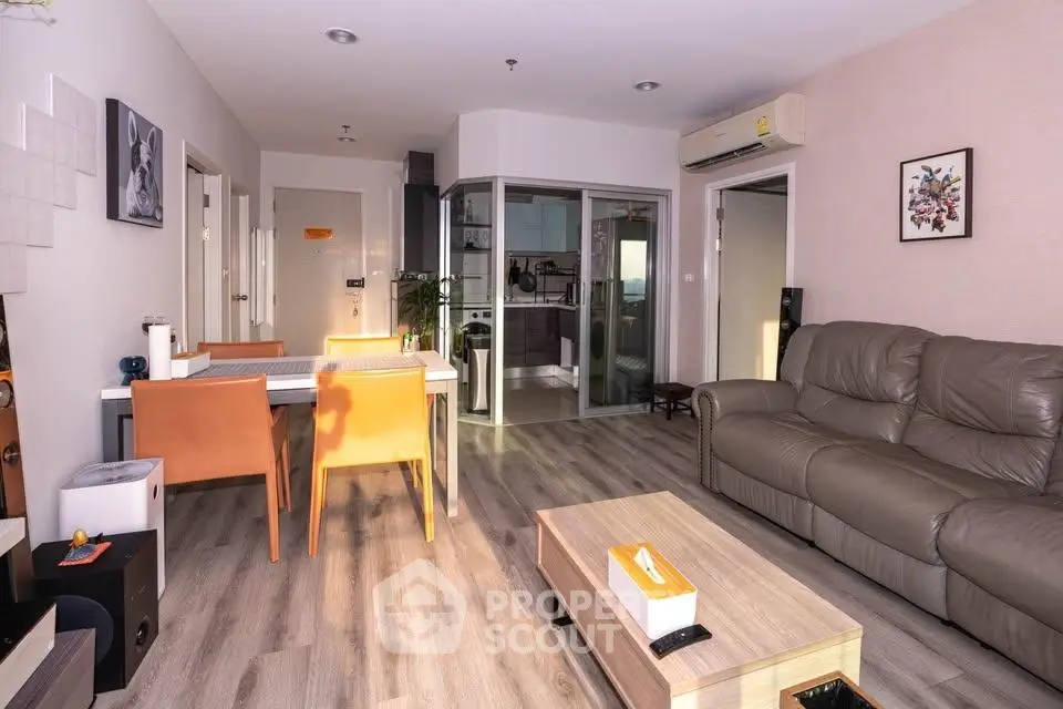 Modern living room with stylish furniture and open kitchen layout, featuring a cozy leather sofa and dining area.