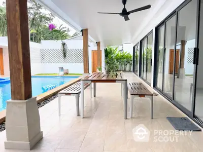 Luxurious poolside patio with modern seating and ceiling fan, perfect for outdoor relaxation.