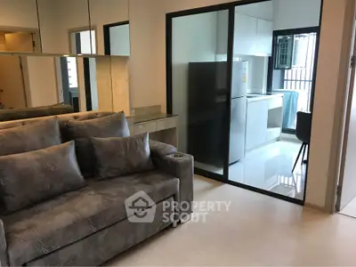 Modern apartment with sleek kitchen and cozy living room featuring stylish sofa and mirrored wall.
