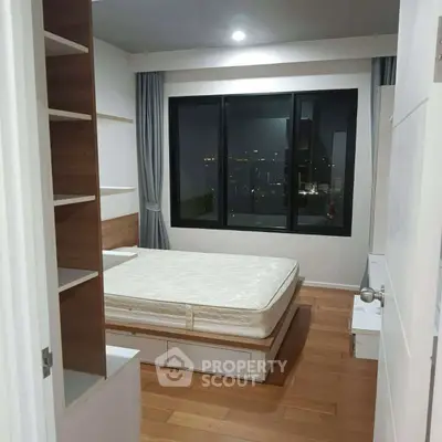 Modern bedroom with city view, featuring sleek design and ample storage space.