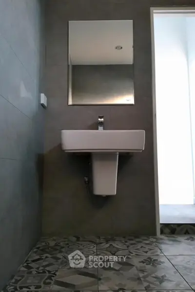 Sleek modern bathroom with stylish gray tiles and designer sink, complemented by a large mirror, exuding contemporary elegance.