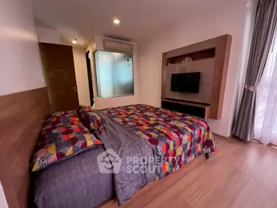 Modern bedroom with stylish decor and natural light, featuring a cozy bed and wall-mounted TV.