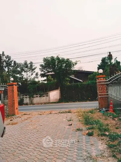 Charming suburban driveway with brick pillars and lush greenery, perfect for a serene lifestyle.