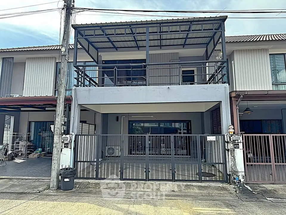 Modern townhouse with spacious balcony and gated entrance in a suburban neighborhood.