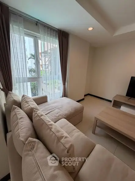 Cozy living room with plush sofa and natural light through large window.