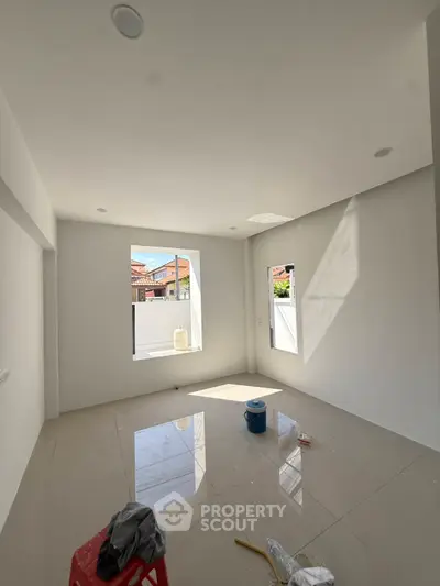 Spacious unfurnished room with large window and glossy tiled floor, perfect for customization.