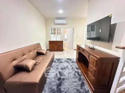 Cozy living room with plush sofa, stylish TV stand, and modern air conditioning unit.