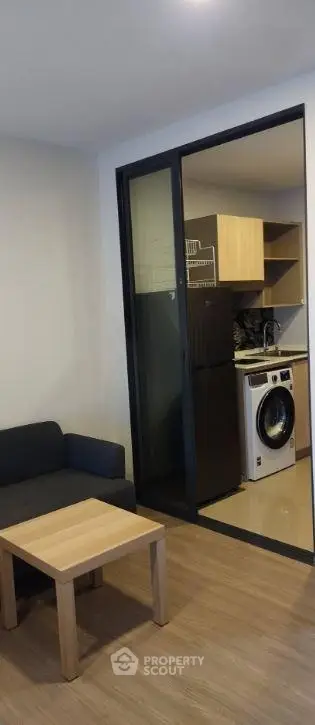 Modern apartment with cozy living room and compact kitchen featuring a washing machine.