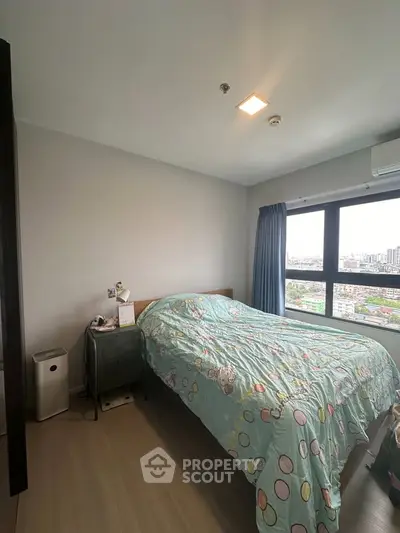 Cozy bedroom with large window offering city views, featuring a neatly made bed and modern decor.