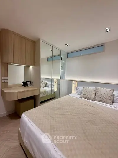 Modern bedroom with elegant decor and mirrored wardrobe in a cozy apartment.