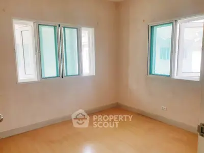 Bright empty room with wooden flooring and large windows in modern home