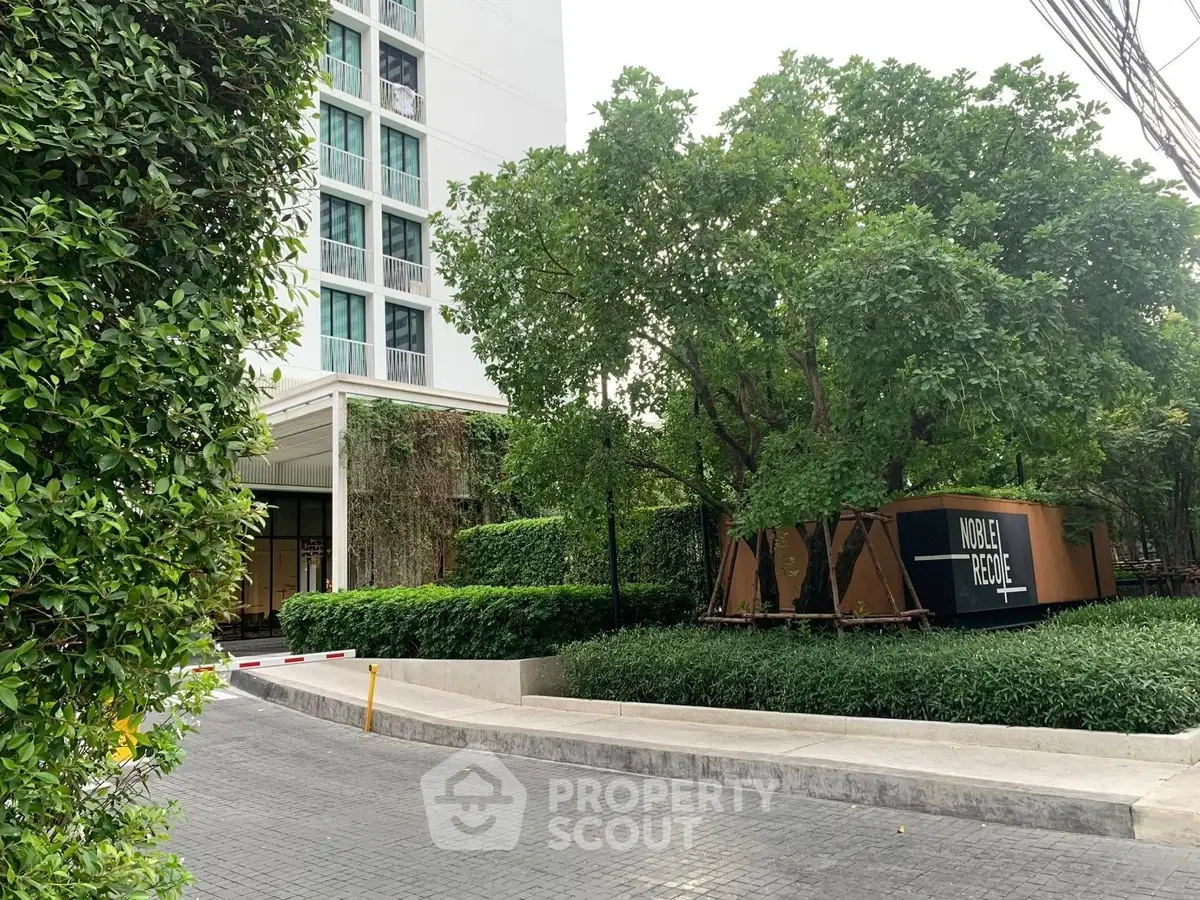 Modern building entrance with lush greenery and paved driveway