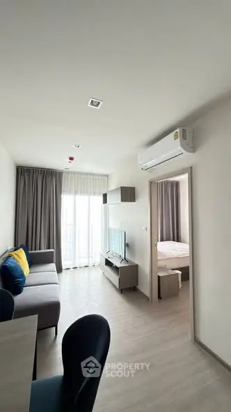 Modern apartment living room with cozy sofa and open bedroom view.