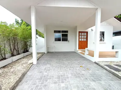 Charming white house entrance with tiled patio and lush greenery