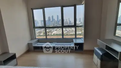 Spacious living room with large windows offering a panoramic city view, modern design, and ample natural light.