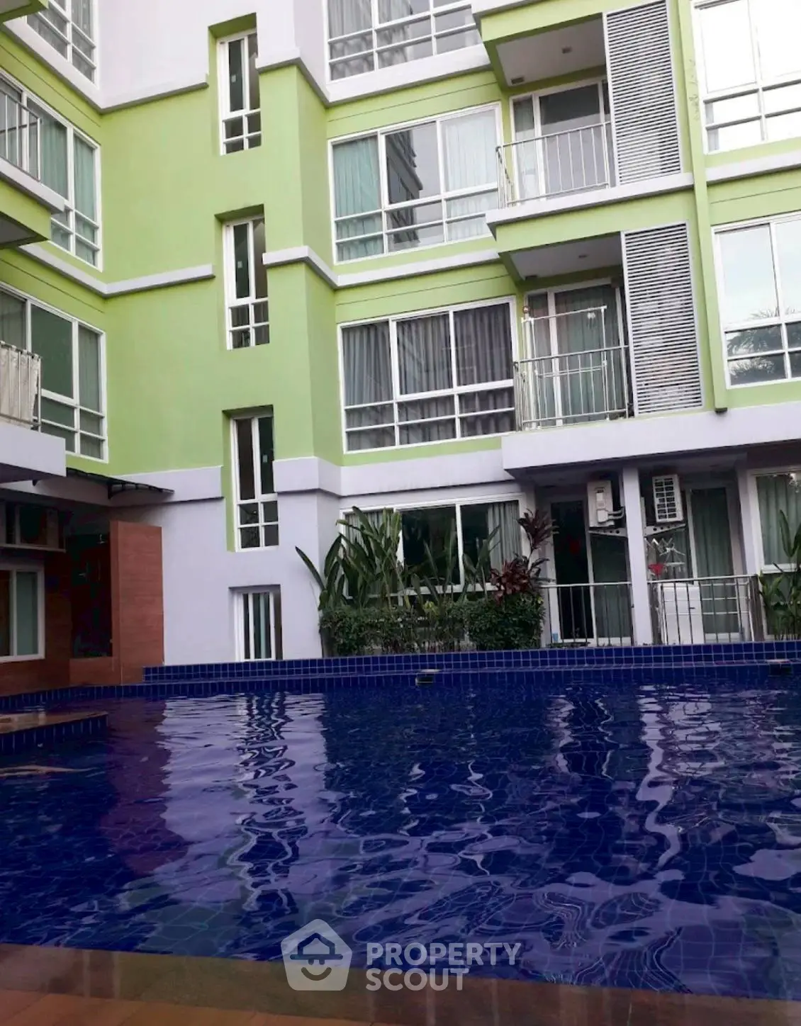 Modern apartment building with a refreshing pool and lush greenery.