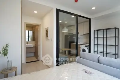 Modern studio apartment with open layout, featuring a cozy living area and a compact kitchen with washing machine.