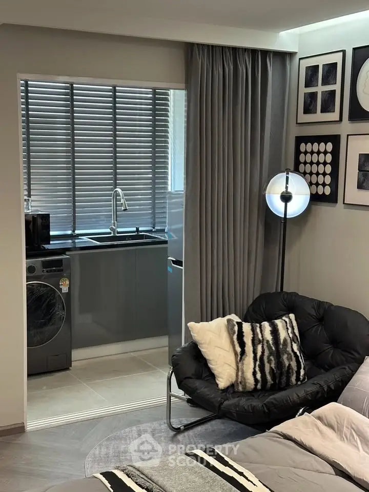 Modern studio apartment with cozy seating and compact kitchen area.