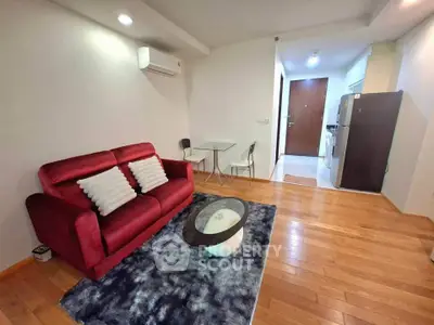 Modern living room with red sofa, wooden flooring, and compact dining area in open layout apartment.