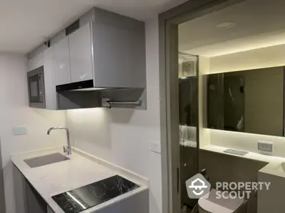 Modern compact kitchen with sleek cabinetry and adjacent bathroom