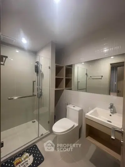 Modern bathroom with glass shower and sleek fixtures in contemporary apartment.