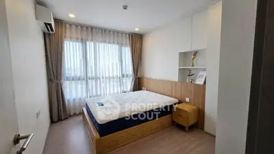 Modern bedroom with large window and stylish decor in a contemporary apartment.