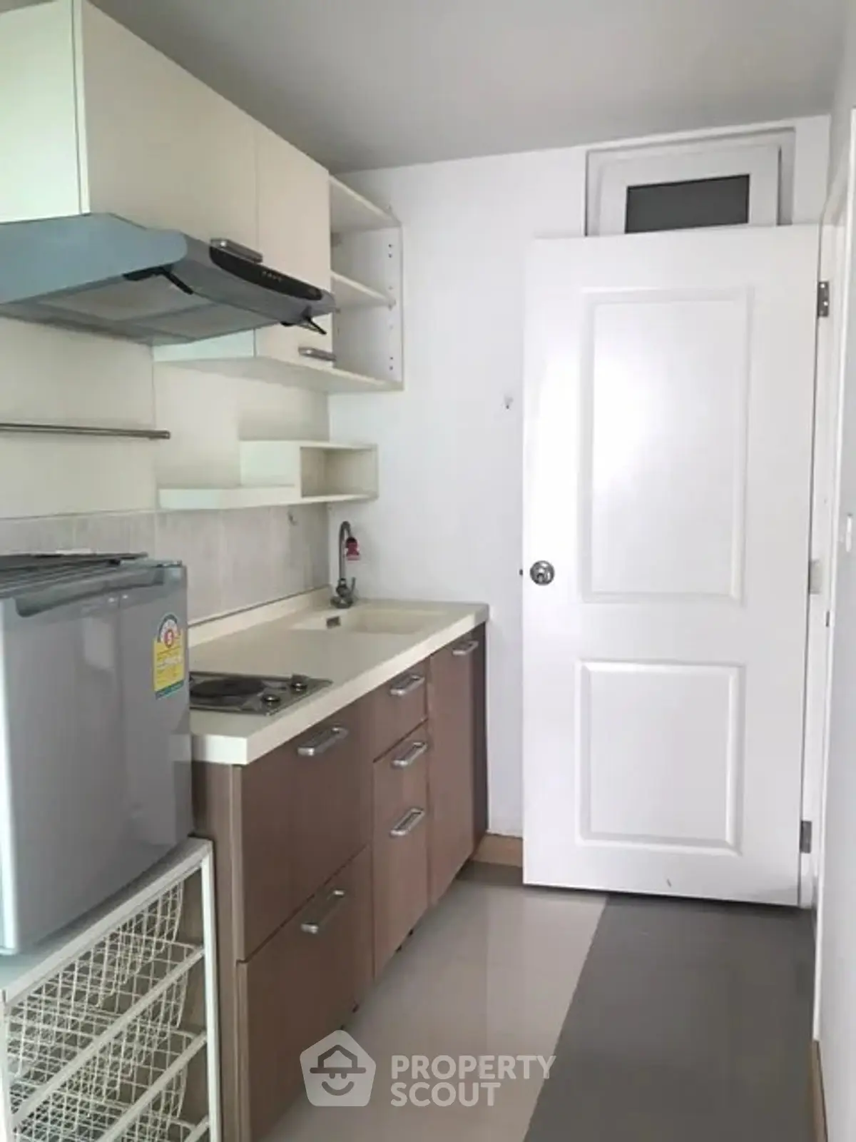 Compact kitchen with modern cabinetry and small fridge in cozy apartment