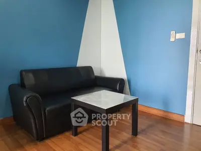 Modern living room with blue accent wall and sleek black sofa