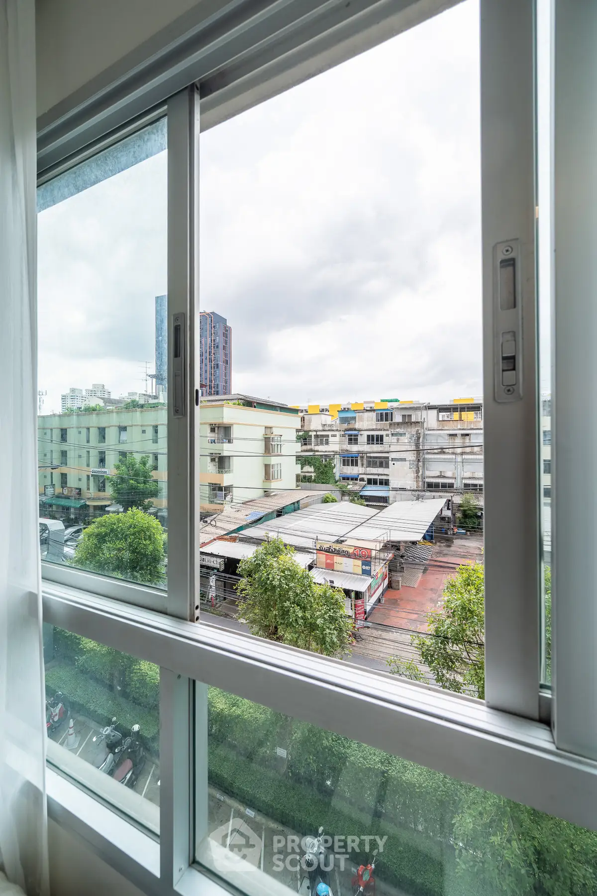 Bright window view showcasing urban landscape with buildings and greenery, perfect for city living.