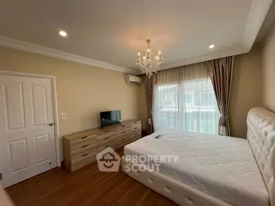 Spacious bedroom with elegant chandelier and natural light in modern apartment