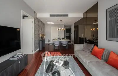 Modern living room with stylish decor and open dining area, featuring sleek furniture and warm lighting.