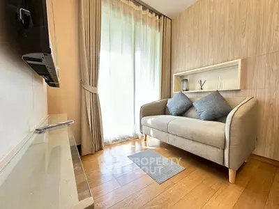 Cozy living room with natural light, wooden flooring, and modern sofa, perfect for relaxation.