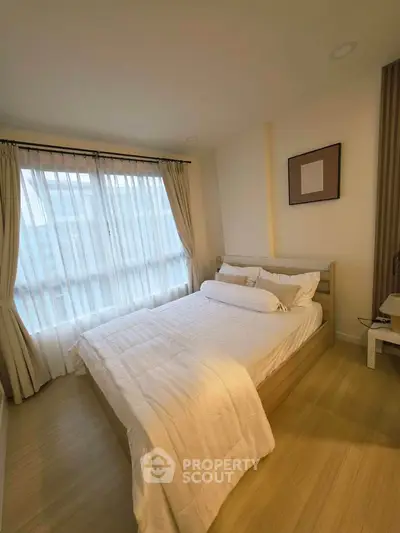 Cozy bedroom with natural light and modern decor, featuring a comfortable bed and stylish curtains.