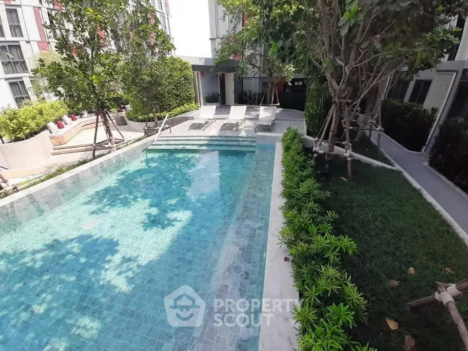 Luxurious residential pool area with lush greenery and sun loungers, perfect for relaxation.
