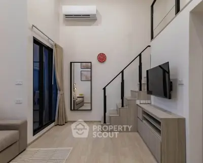 Modern living room with high ceiling, staircase, and wall-mounted TV in stylish apartment.