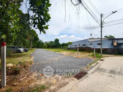 Spacious land plot with gravel road access, ideal for development in a serene neighborhood.