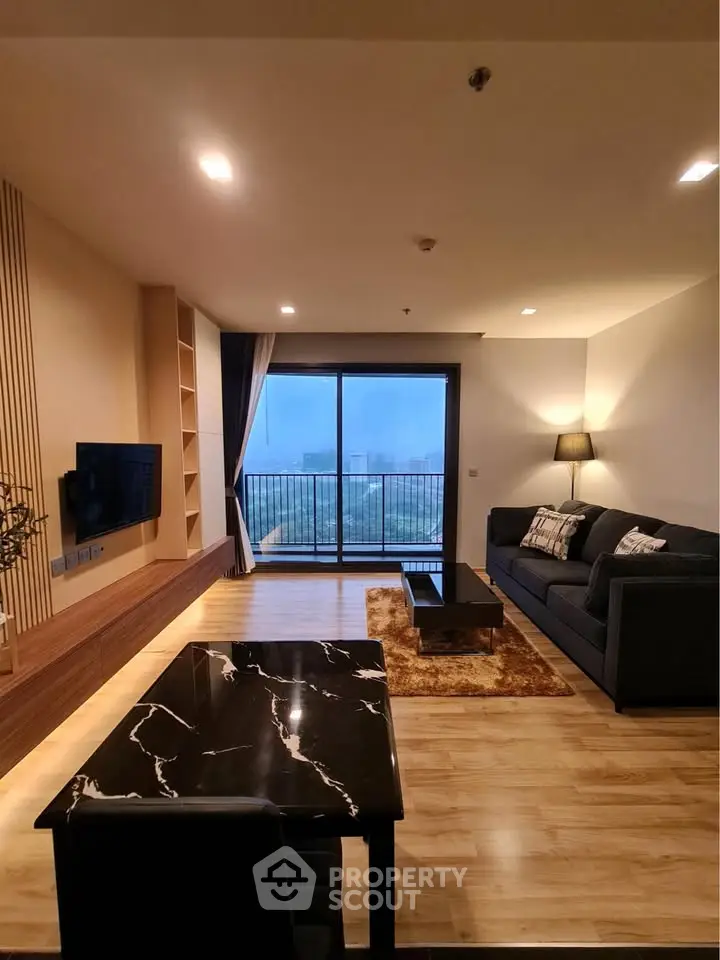 Modern living room with balcony view, stylish furniture, and elegant lighting in a high-rise apartment.