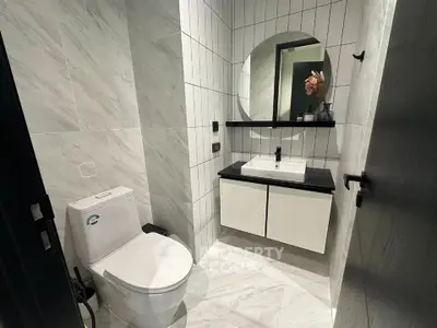 Modern bathroom with sleek design, featuring a round mirror and stylish fixtures.