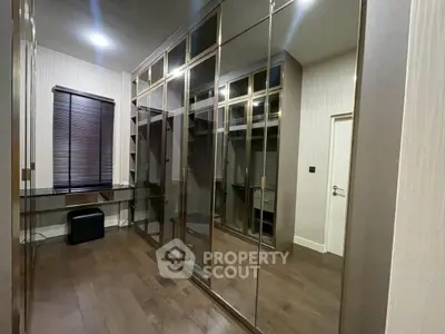Luxurious walk-in closet with mirrored wardrobes and elegant wooden flooring.