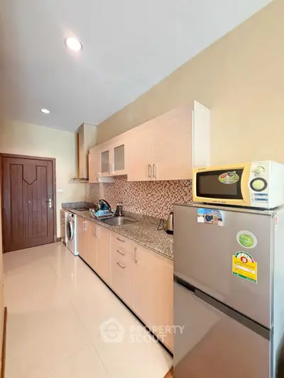 Modern kitchen with sleek cabinets, granite countertops, and stainless steel appliances in a cozy apartment.