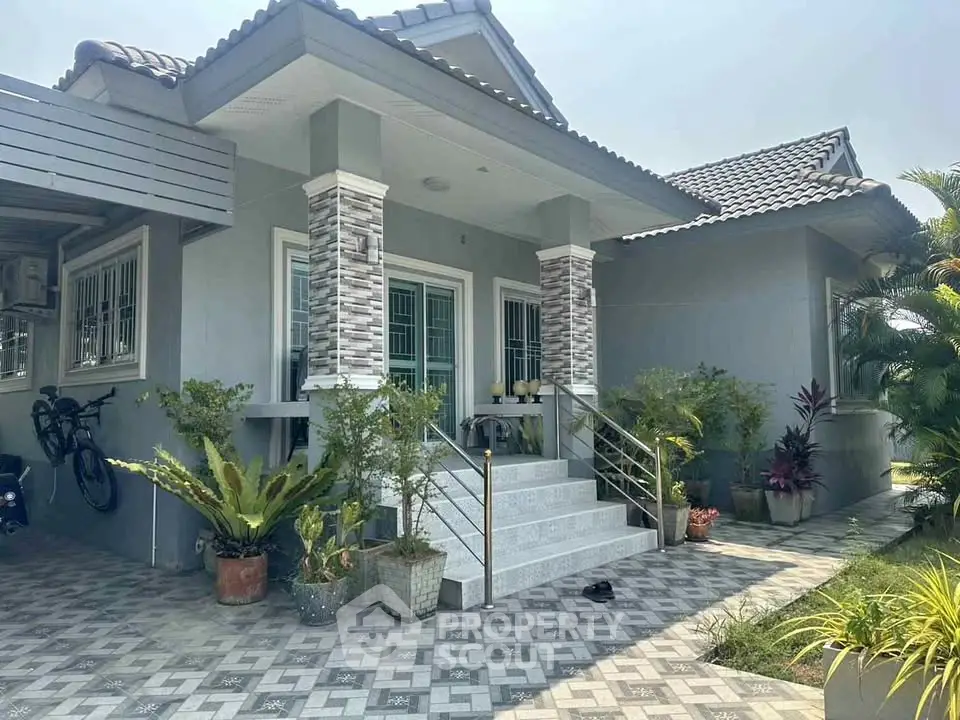 Charming single-story home with tiled roof, lush garden, and inviting entrance.