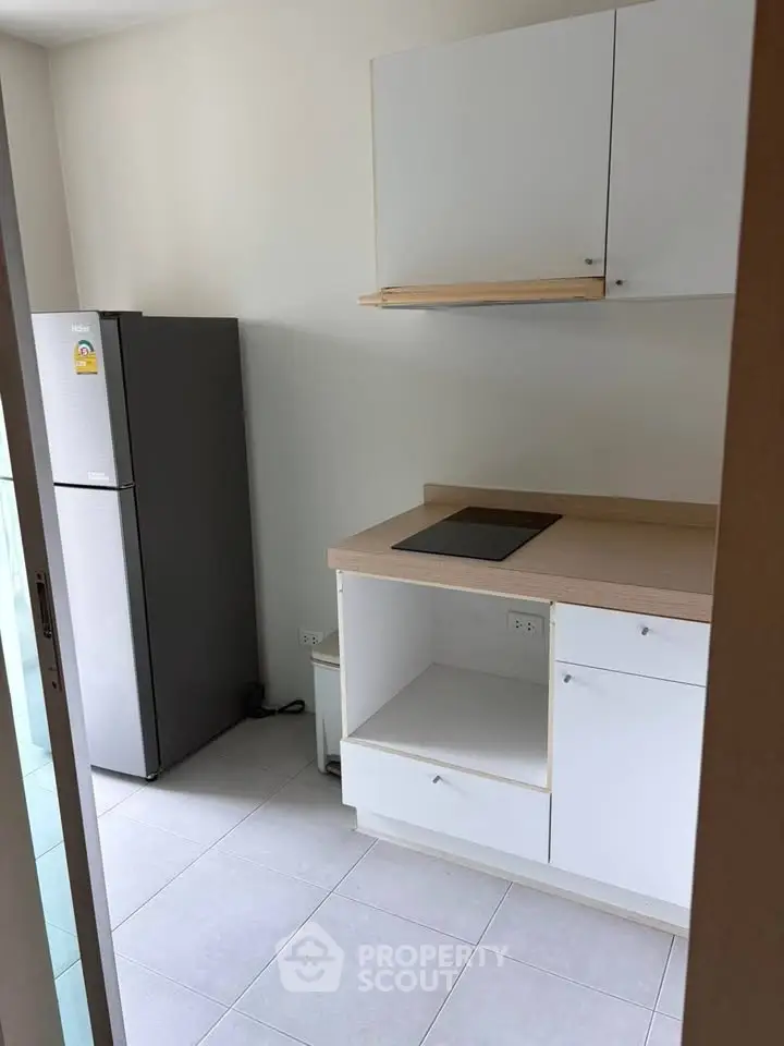 Modern kitchen with sleek cabinets and built-in cooktop, featuring a spacious fridge and minimalist design.