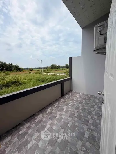 Spacious balcony with scenic view of lush greenery and open sky, perfect for relaxation.