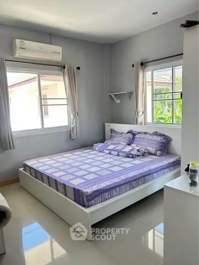Bright and cozy bedroom with large windows and modern air conditioning unit.