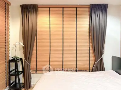 Cozy bedroom with elegant curtains and wooden blinds, perfect for a serene retreat.