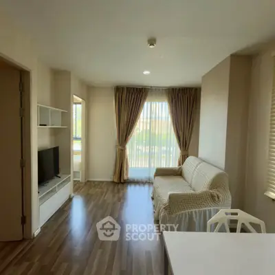 Bright living room with cozy sofa and large window, featuring elegant curtains and modern flooring.
