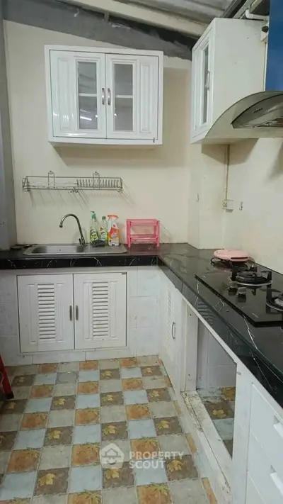 Compact kitchen with gas stove and black countertops in cozy apartment.