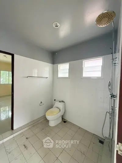 Spacious bathroom with modern shower and toilet in a bright, tiled setting.