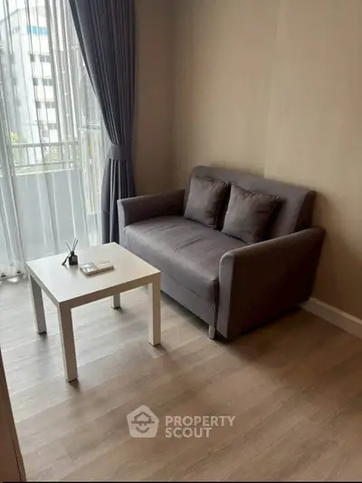 Cozy living room with modern gray sofa and white coffee table near large window with city view.