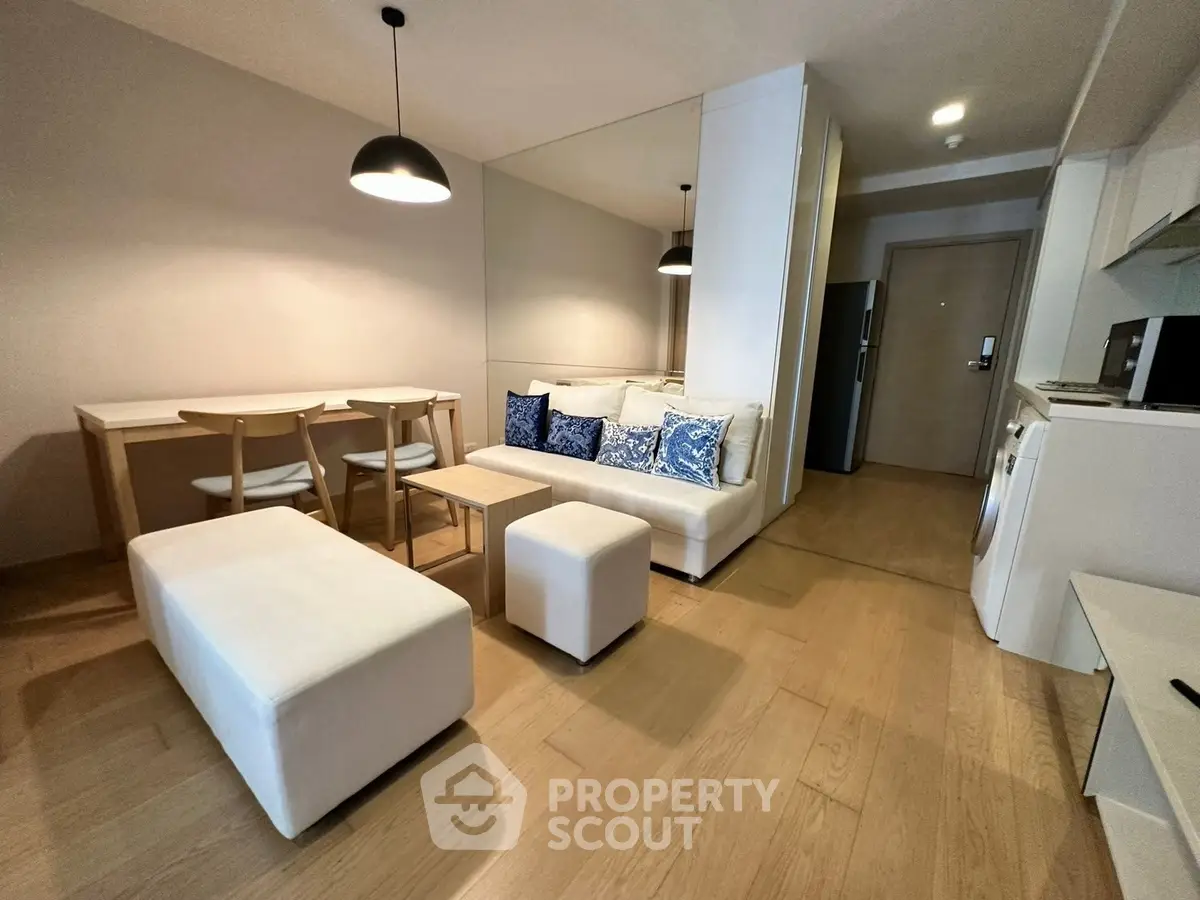 Modern living room with dining area and kitchen, featuring stylish lighting and wooden flooring.
